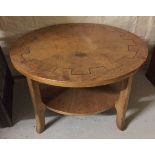 A circular oak coffee table with wheel design to top. 86cm diameter.