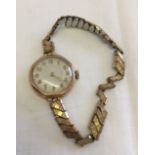 A 9ct gold cased ladies watch with a rolled gold expandable strap. In working order.