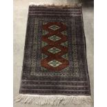 A small wool prayer rug in rust brown, black and grey colours. 98 x 62cm.