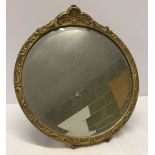 Round bevel edged mirror with gilt frame, approx 32cm across. Has stand on the back so can be