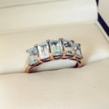 9ct gold dress ring set with a row of 5 large baguette cut blue topaz stones with small diamonds set