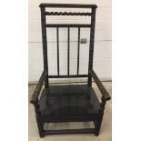 An antique dark oak chair with carved arms and back rails and barley twist decoration.