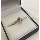 18ct gold ring set with a central ruby surrounded by diamonds in a platinum setting. Size L1/2,