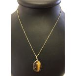 9ct gold pendant set with a large oval cabouchon Tigers Eye stone, on a 9ct gold fine box chain.