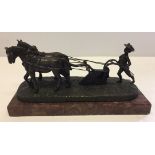 Small bronze of a farmer ploughing.