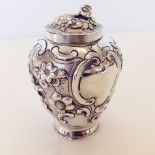 A Georgian silver lidded jar with flower decoration and vacant cartouches 1814 London 11cm tall.