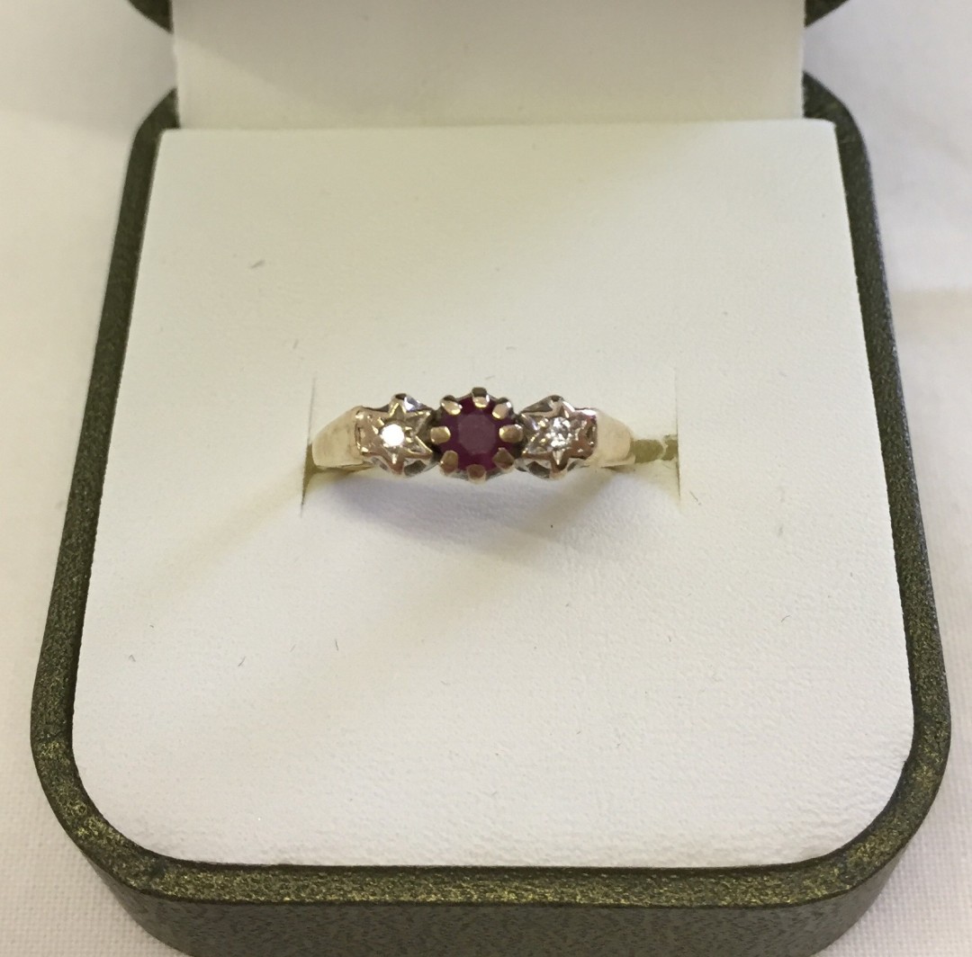 9ct gold 3 stone ring set with central ruby and 2 small diamonds in illusion settings. Size K1/2,