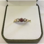 9ct gold 3 stone ring set with central ruby and 2 small diamonds in illusion settings. Size K1/2,