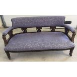 A Victorian dark oak framed settee with blue floral upholstery & ceramic castor feet. Approx 145 x