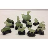 12 small pieces of oriental Jade on wooden plinths.