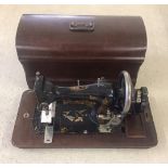 A vintage hand sewing machine in wooden case.