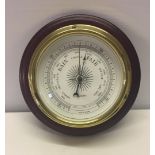 A modern brass cased wall barometer on wooden plinth.