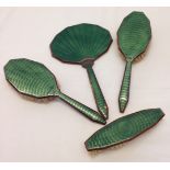 An Art Deco dressing table set of 3 brushes and mirror with green guilloche enamel decoration.