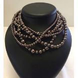 A 6 strand bead necklace with bronze colour beads of various sizes.