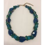 Statement necklace set with large faceted glass beads in teal and blue.