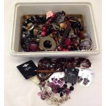 A container of costume jewellery to include earrings and necklaces.