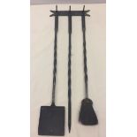 A wrought iron wall mounted companion set with twist handle decoration.