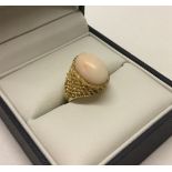 A yellow gold ladies ring set with central coral stone.