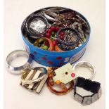 A tin of modern costume jewellery mostly bangles.