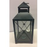 A green metal garden lantern with glass panels.