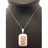 A large rectangular silver locket with engraving to front & back. On a silver chain.