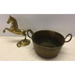 A brass two handled pan with a brass horse.