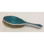 A silver hairbrush with teal coloured guilloche enamel.