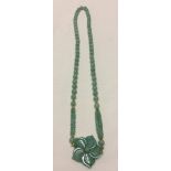 A large Jade bead necklace with central flower shaped pendant.