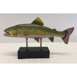 A large cold painted metal trout set onto a wooden base.