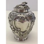 A Georgian silver lidded jar with floral decoration and vacant cartouches.