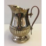 A silver plated water jug with leather handle.