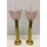 2 oil lamps made from brass shell cases with pink glass shades.