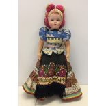 A fully jointed fabric bodied vintage doll in traditional dress.