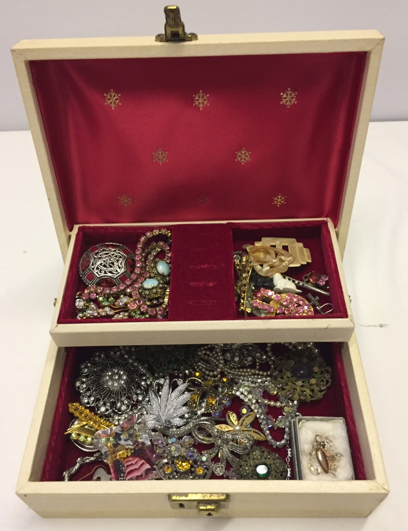 A vintage cream jewellery box containing a good quantity of vintage jewellery.