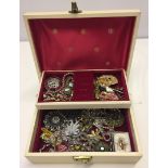 A vintage cream jewellery box containing a good quantity of vintage jewellery.