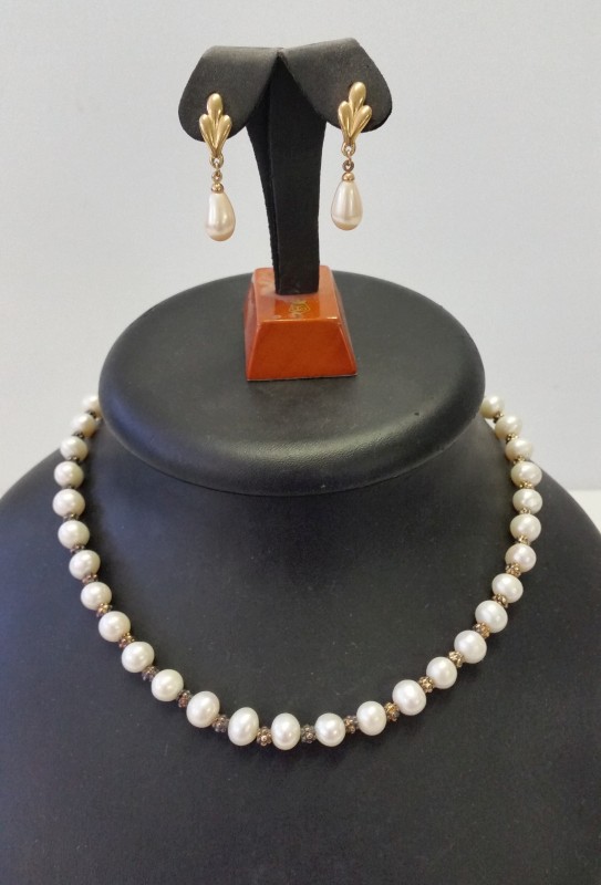 A freshwater pearl necklace together with a pair of Trifari faux pearl earrings.