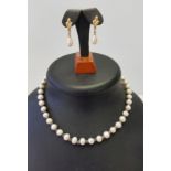 A freshwater pearl necklace together with a pair of Trifari faux pearl earrings.