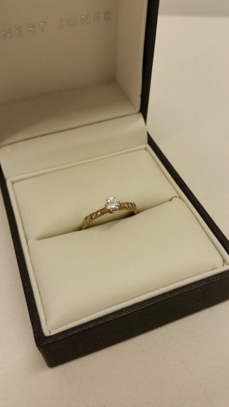 A 9ct gold diamond solitaire ring, set with 3 stones to each shoulder.