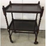 A dark wood vintage tea trolley with barley twist legs.