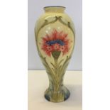 A Tall bulbous tube lined vase with floral decoration.