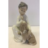 A Lladro figurine of a boy with his dog.