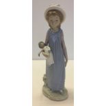 A Lladro figurine of a young girl holding her doll.