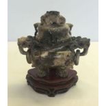 A soapstone 3 footed lidded incense urn on carved wooden base.