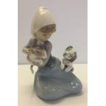 A Lladro figurine of a young girl in a head scarf with a cat and a puppy.