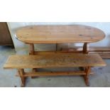 An oval pine kitchen table with pine bench.