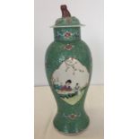 A decorative Chinese ceramic lidded jar with painted panels on a turquoise background.
