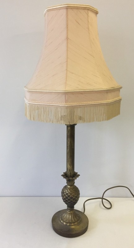 A brass effect table lamp with pineapple decoration and peach coloured shade.