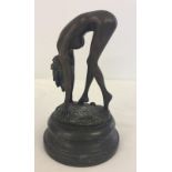 A bronze of a naked lady bending over. On marble base.