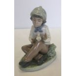 A boxed Nao porcelain figurine of a boy sitting with a dove.