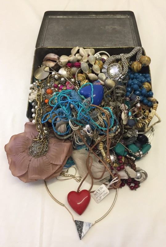 A tin of mixed costume jewellery to include necklaces.